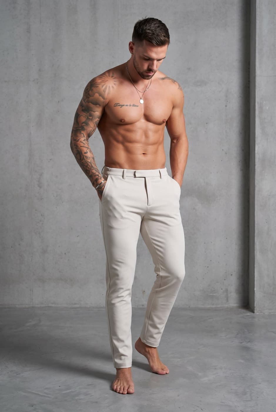A generated ad still: a model in cream trousers against a concrete wall.